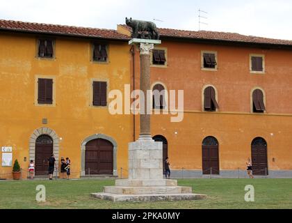 Lupa Capitolina, colonna sormontata dalla Lupa Capitolina in bronzo, in Piazza del Duomo, Palazzo dell'Opera sullo sfondo, Pisa, Italia Foto Stock