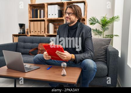 Bell'uomo di mezza età che lavora all'ufficio di consultazione sorridendo guardando al lato e fissando via il pensiero. Foto Stock