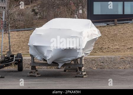 daycruiser sportivo adagiato su terreni avvolti in plastica bianca. Foto Stock