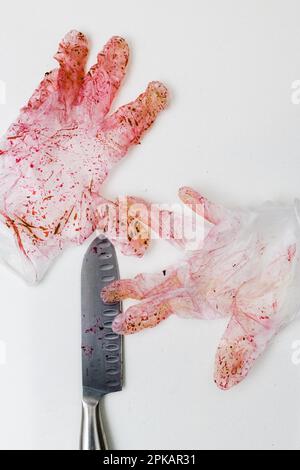 Guanto monouso con coltello scolorito di colore rosso su una superficie bianca Foto Stock