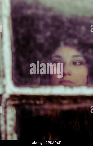 Ragazza dietro la vecchia finestra muntin Foto Stock