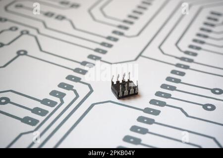 circuito integrato a 8 gambe. Componente semiconduttore su uno sfondo dello schema di circuito stampato elettronico. Foto Stock