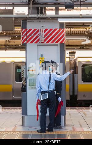 Giappone, Honshu, Tokyo, Stazione ferroviaria di Shinjuku, due guardie della piattaforma Foto Stock