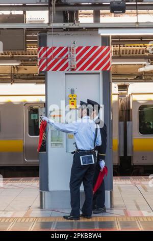 Giappone, Honshu, Tokyo, Stazione ferroviaria di Shinjuku, due guardie della piattaforma Foto Stock