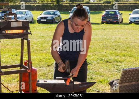 Inghilterra, Dorset, Shaftesbury, l'annuale Wessex Heavy Horse Show and Country Fair, Female Farrier Making Horse Shoe Foto Stock
