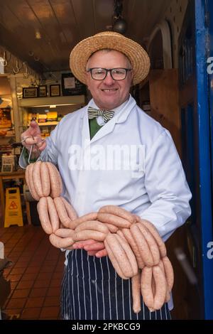 Inghilterra, Dorset, Bridport, Ritratto del macellaio del maestro Richard Balson che tiene Una stringa delle salsicce Foto Stock