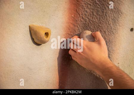 Primo piano delle mani di un arrampicatore che afferra una maniglia di arrampicata Foto Stock