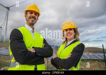 Due ingegneri sorridenti con braccia piegate in una centrale solare. Foto Stock