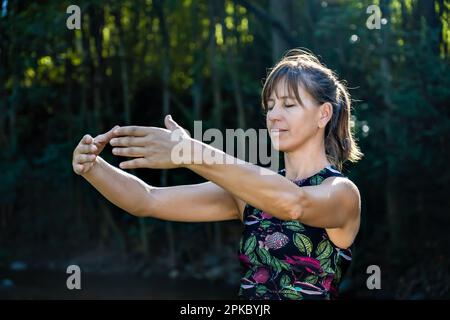 Qigong Master femminile pratica Arti Marziali Cinesi in natura. La luce del sole illumina la scena Foto Stock