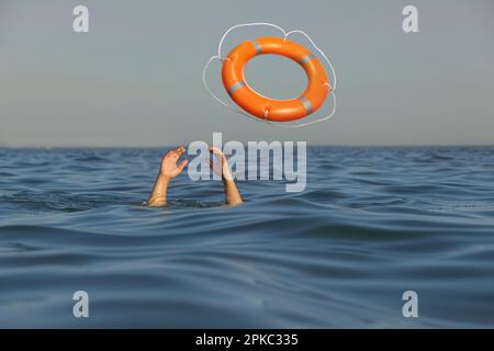 Annegando l'uomo con le mani sollevate ottenendo la cintura di sicurezza in mare Foto Stock