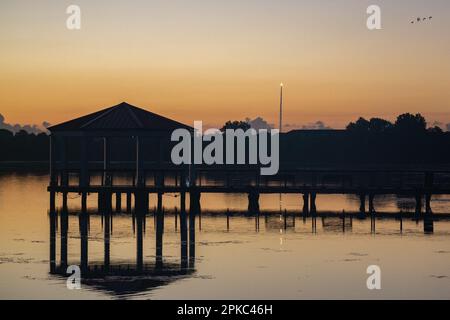 Una foto di un gazebo con un molo sul lago con un riflesso al crepuscolo, Baldwin Park, Orlando Foto Stock