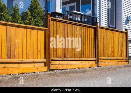 Nuovo recinto di legno intorno alla casa. Recinzione di legno. Foto di strada, nessuno, fuoco selettivo. Immobiliare esterno Casa anteriore in una giornata di sole Foto Stock