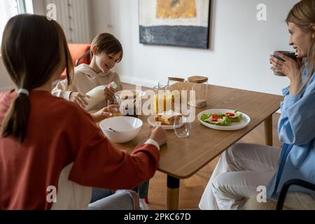 Buona colazione per tutta la famiglia mentre si siede al tavolo da cucina Foto Stock