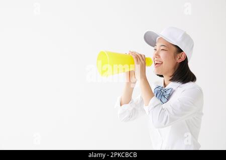 Ragazza della scuola superiore che indossa un cappello che tiene un megafono e urla Foto Stock