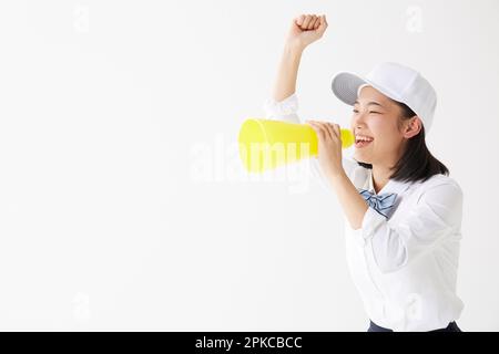 Ragazza della scuola superiore che indossa un cappello che tiene un megafono e urla Foto Stock