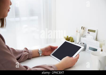 Donna con un tablet su un tavolo bianco Foto Stock