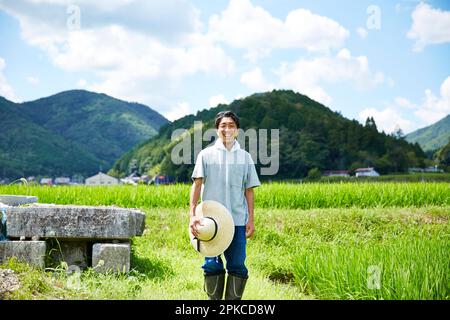 Uomo sorridente in piedi tra risaie Foto Stock