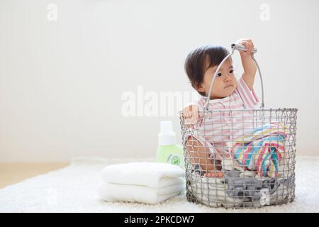 Baby in cesto lavanderia con lavanderia Foto Stock