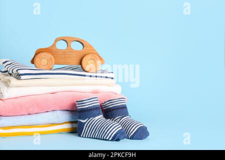 Pila di vestiti per bambini, calze e giocattolo di legno su sfondo colorato Foto Stock