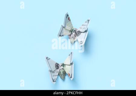 Farfalle Origami fatte di banconote in dollari su sfondo blu Foto Stock