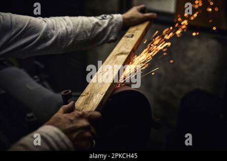 Un uomo che lavora in una fabbrica di posate con scintille che volano Foto Stock