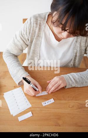 Una donna che scrive il suo nome su un tag nome Foto Stock