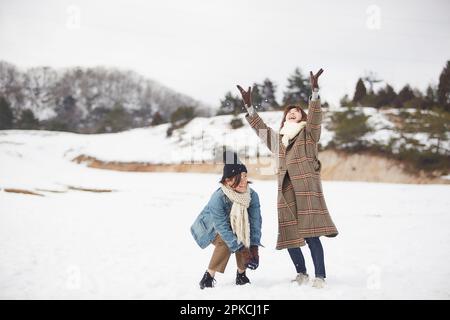 Due donne che giocano in una piazza innevata Foto Stock