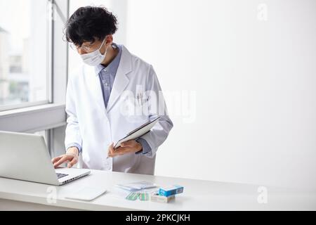 Uomo in bianco che lavora a un computer portatile al banco Foto Stock
