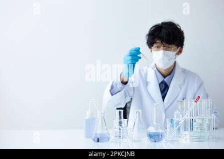 Uomo in bianco che fa un esperimento in uno spazio bianco Foto Stock