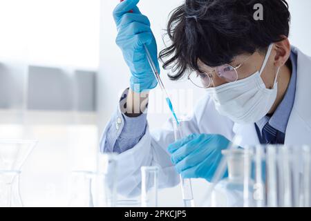 Uomo in camice da laboratorio sperimentando in uno spazio bianco Foto Stock