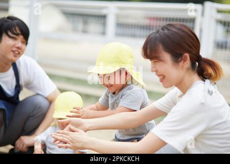 Insegnante di scuola materna e bambini che giocano nel sandbox Foto Stock