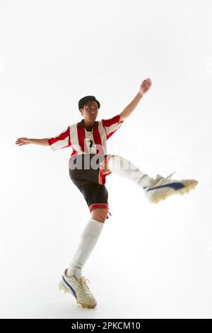 Giocatore di calcio calci una palla e dondolando la gamba Foto Stock