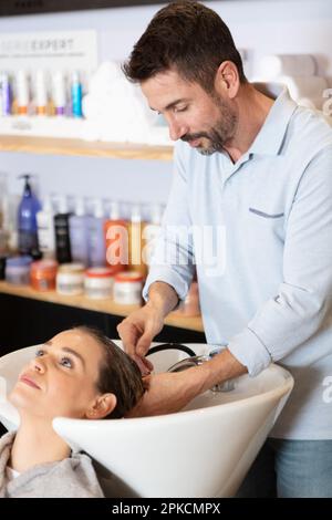 parrucchiera maschile lavaggio capelli donna in salon lavello Foto Stock