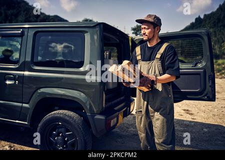 Uomo che prende legna da ardere fuori dall'auto Foto Stock