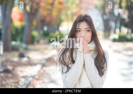 Una donna nel suo 20s a piedi lungo un viale alberato a fine autunno Foto Stock