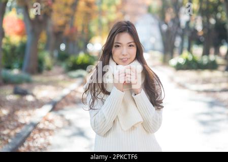 Una donna nel suo 20s a piedi lungo un viale alberato a fine autunno Foto Stock