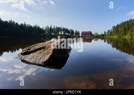 Hornisgrinde, Germania - 11 agosto 2021: Lago (Mummelsee) nella Foresta Nera di mattina presto. Hotel di montagna per pernottamenti sull'altra palude Foto Stock