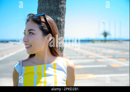 donna che viaggia in una località balneare appoggiata a una palma Foto Stock