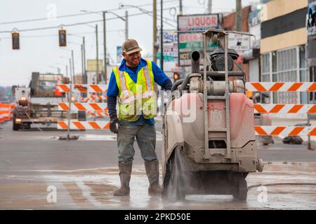 Detroit, Michigan, Un operaio gestisce una sega in cemento a piedi come parte di un progetto per creare piste ciclabili protette, marciapiedi più ampi e per lo stabilimento Foto Stock