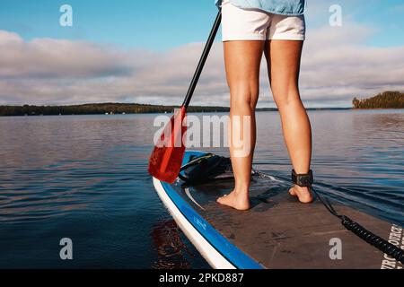 Vai dove ti porta l'acqua. una donna irriconoscibile paddle boarding su un lago. Foto Stock