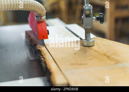 Concentratevi sulla lama della sega da tavolo che taglia la tavola di legno. Interni e attrezzature per officine di lavorazione del legno. Primo piano. Foto di alta qualità Foto Stock
