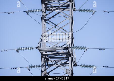 La torre in acciaio di tipo a traliccio è sotto il cielo blu come parte della linea ad alta tensione. Dettagli della linea elettrica aerea Foto Stock