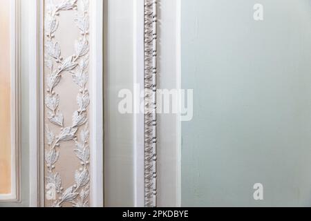 Parete verde chiaro con classica decorazione in stucco, frammento astratto interno con ornamento floreale a rilievo bianco Foto Stock