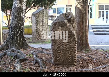 Zvorrnik, Bosnia-Erzegovina – Febbraio 2023: Pietre lapidi Stecak-medievali di fronte alla biblioteca. Foto Stock