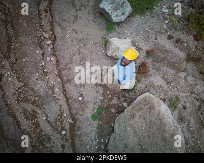 Vista dall'alto di un ingegnere afro-americano nel cantiere con elmetto e occhiali di protezione Foto Stock