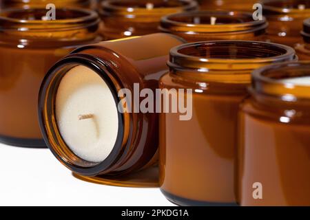Un set di diversi aromi di candele di soia e di cera di cocco in vasi di vetro marrone. Candela profumata e calmante. Candele naturali essenziali in vaso d'ambra. Aromaterapia Foto Stock