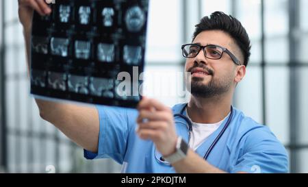 Il medico caucasico in uniforme guarda i raggi X. Foto Stock