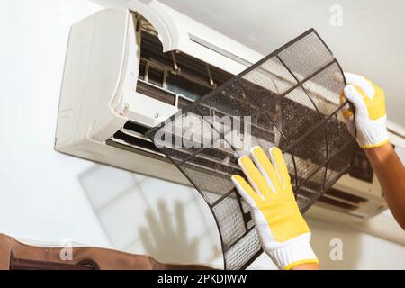 L'uomo che rimuove il filtro dell'aria nel condizionatore d'aria viene pulito per una buona salute a casa. Foto Stock