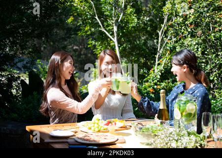 Tre donne sorridenti che brinda a una festa in giardino Foto Stock