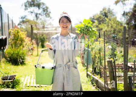 Una donna sorride con ravanelli raccolti nel campo Foto Stock